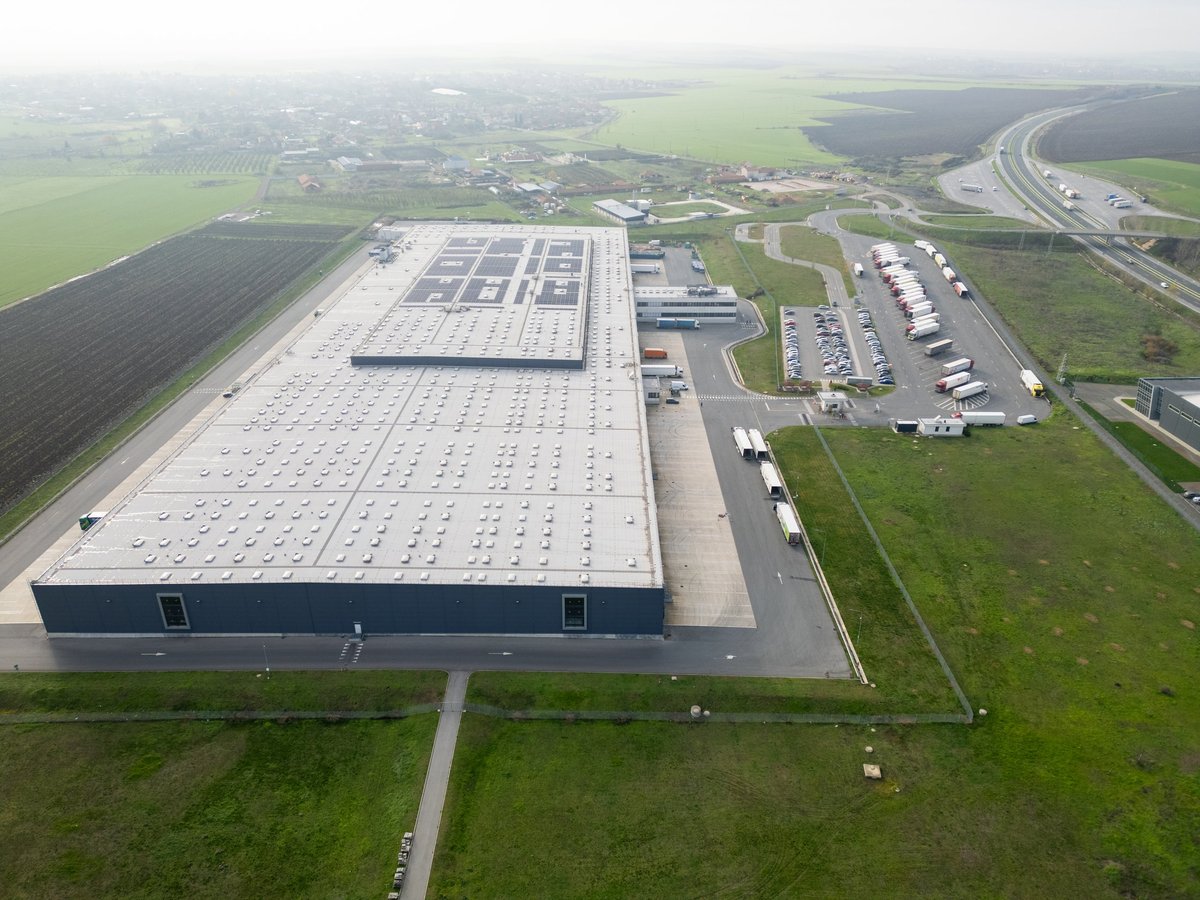Aerial view of a large logistics distribution warehouse with trucks